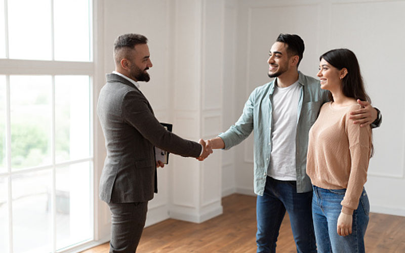 realtor and couple shaking hands after buying a home