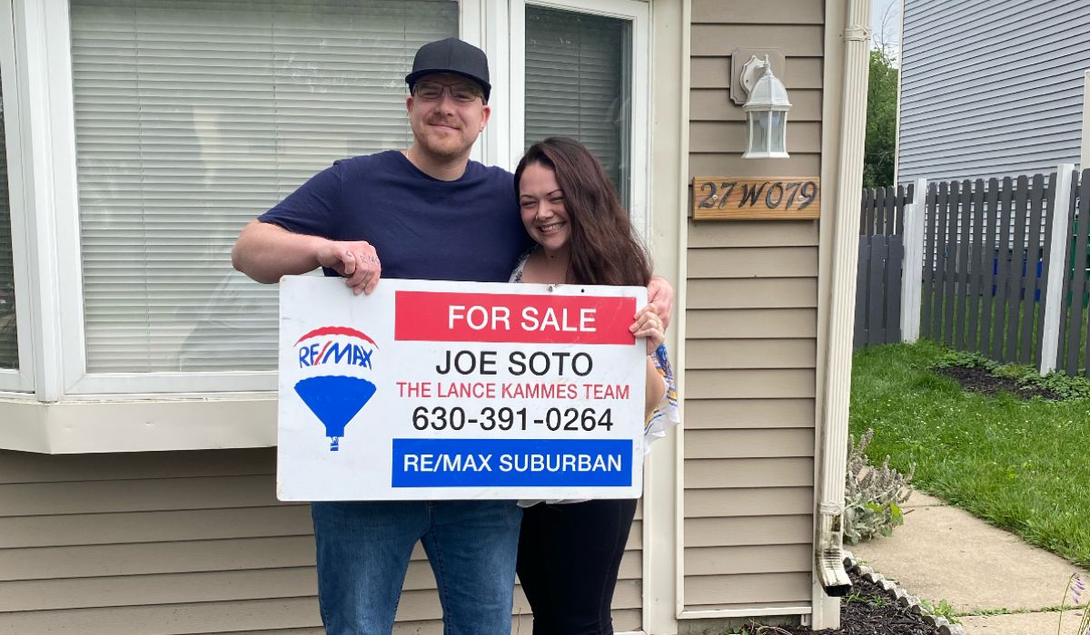 a couple holding a signage for sale